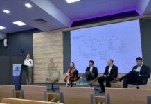 Human AI Collaboration Summit / Kulturforum Warschau Foto eines Podiumsgesprächs an der Kozminski University. Prof. Iris Eisenberger spricht am Rednerpult, während vier weitere Teilnehmerinnen und Teilnehmer auf der Bühne daneben sitzen. Im Hintergrund ist eine Präsentation der Universität Wien zum Thema „Guidelines and Code of Practice on Trans¬parent AI“ zu sehen.