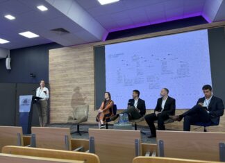 Human AI Collaboration Summit / Kulturforum Warschau Foto eines Podiumsgesprächs an der Kozminski University. Prof. Iris Eisenberger spricht am Rednerpult, während vier weitere Teilnehmerinnen und Teilnehmer auf der Bühne daneben sitzen. Im Hintergrund ist eine Präsentation der Universität Wien zum Thema „Guidelines and Code of Practice on Trans¬parent AI“ zu sehen.