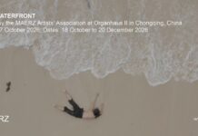 Ausstellung / Generalkonsulat Chengdu Das Bild zeigt eine Luftaufnahme eines sandigen Strandes mit heranrollender Brandung. Im unteren Bildbereich liegt eine Person rücklings im Sand, Arme und Beine leicht angewinkelt. Links oberhalb der Person ist ein kleiner dunkler Gegenstand zu sehen. Über dem Motiv stehen in weißer Schrift der Ausstellungstitel „ON THE WATERFRONT“ sowie Angaben zur Ausstellung im Organhaus II in Chongqing. Unten links befindet sich das MAERZ-Logo, unten rechts die Webadresse.