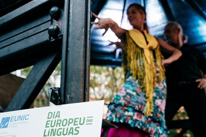 Zwei Personen tanzen bei einer Veranstaltung. Im Vordergrund steht ein Schild zum Europäischen Tag der Sprachen.