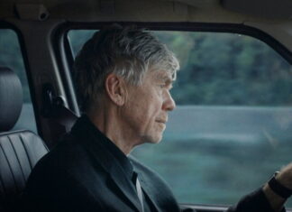 Doclisboa / Botschaft Lissabon Das Bild zeigt den Schauspieler Bobby Sommer, einen älteren Mann, am Steuer eines Autos. Es handelt sich um ein Standbild aus dem Film „London“ von Sebastian Brameshuber.
