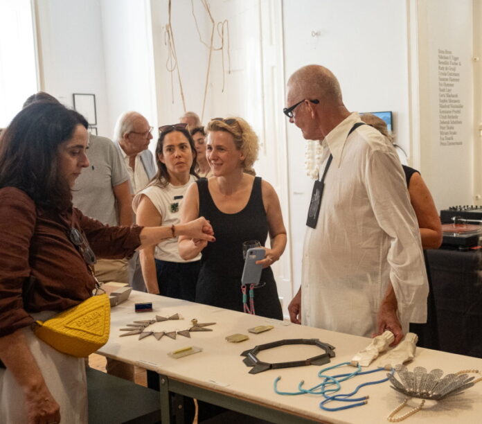 Foto: Guilherme Gouveia Das Bild zeigt die österreichische Schmuckkünstlerin Iris Hummer sowie Besucherinnen und Besucher der Ausstellung.